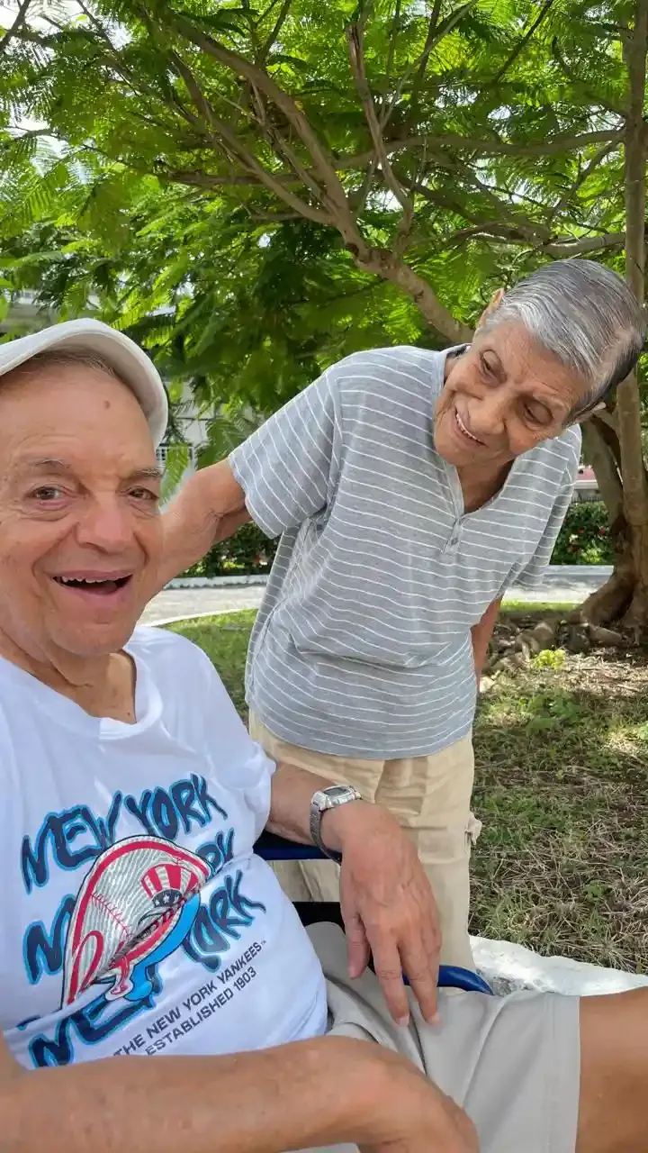Adultos mayores acompañados en un área de jardín durante un día cálido en Panamá