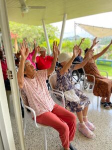 Residentes realizando ejercicios de brazos guiados por una cuidadora.