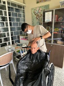 Personal de Golden Paradise ofreciendo cortes y arreglos de cabello al aire libre, en un entorno relajado y natural.